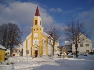 Zimní snímek Náměstí Svobody V Kolovči s dominantou kostela Zvěstování Panny Marie a přilehlou farou